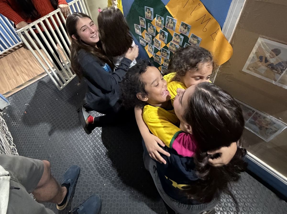 Rise Up Co members hugging children at CEI Espaço Criança on the June 2026 visit