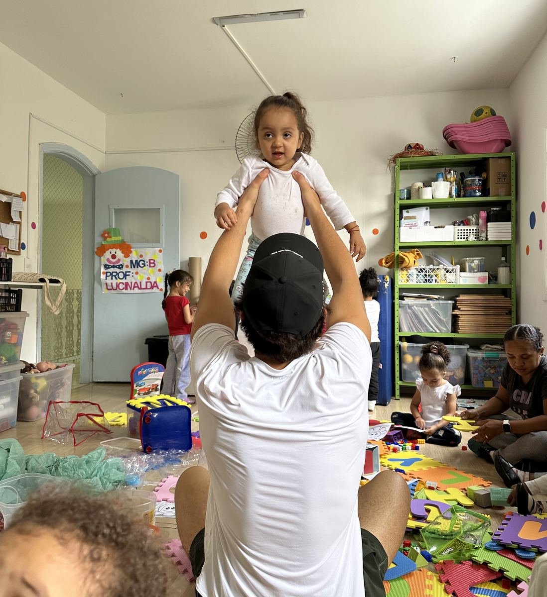 A Rise Up Co leader lifting a smiling toddler in a daycare playroom
