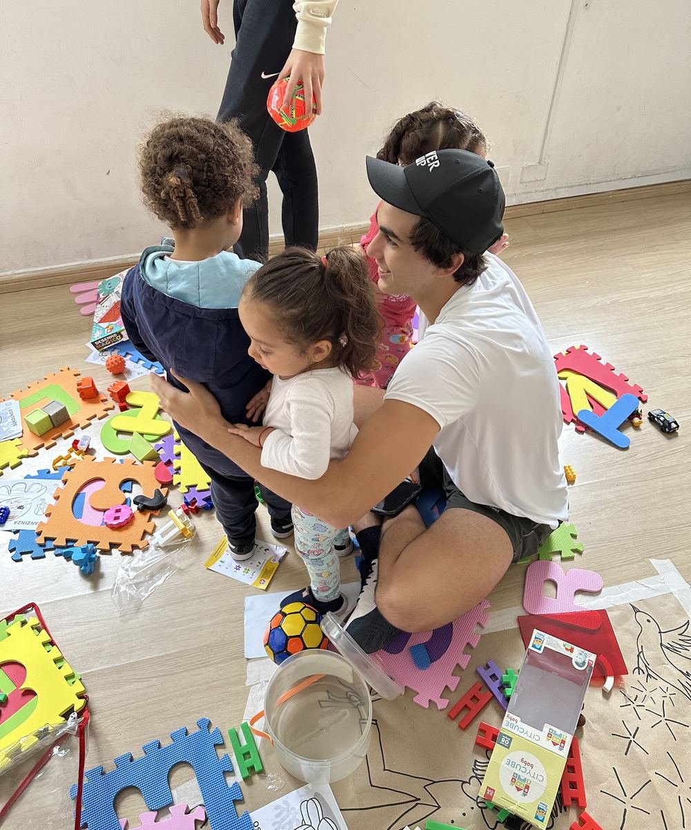 A Rise Up Co leader on the floor with two toddlers among foam puzzle mats