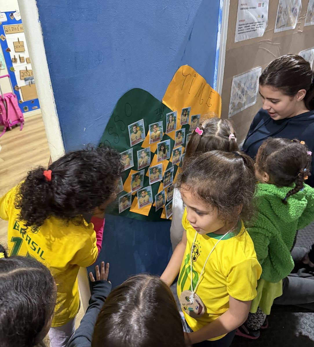 Children in Brazil jerseys showing a Rise Up Co member their wall of football stickers