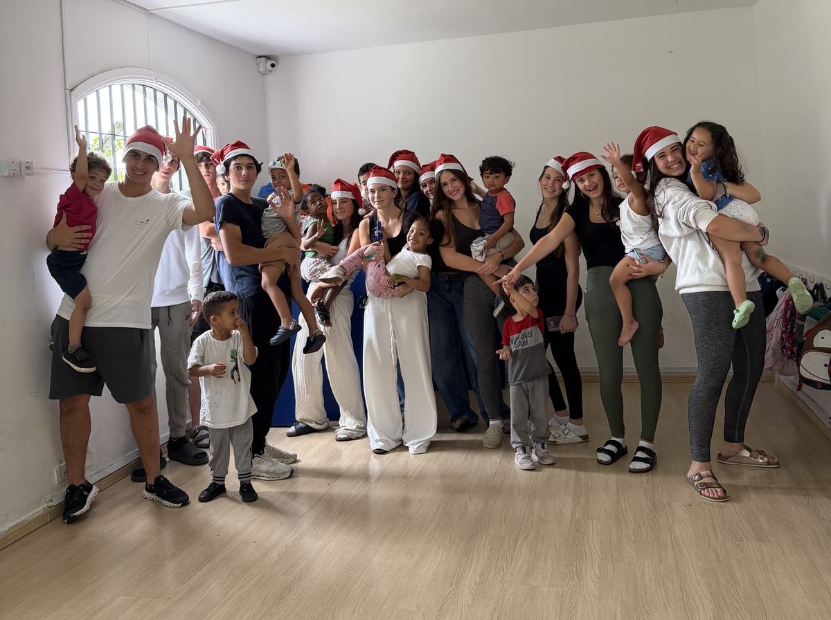 The Rise Up Co team in Santa hats with the daycare children at the Christmas visit